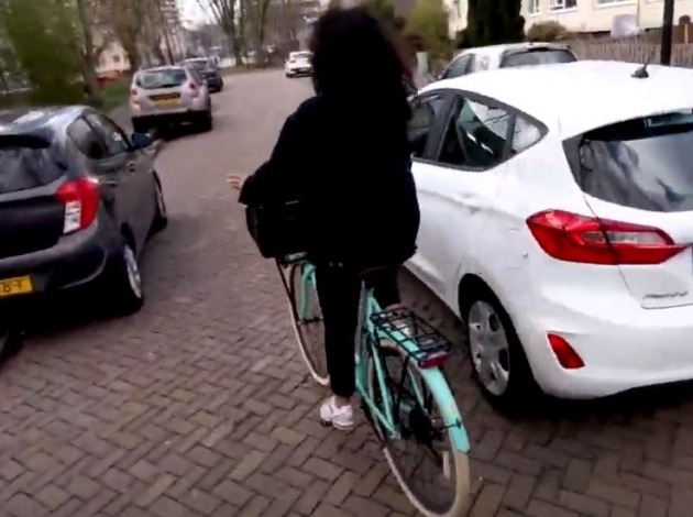 Vrouw fietst langs geparkeerde auto