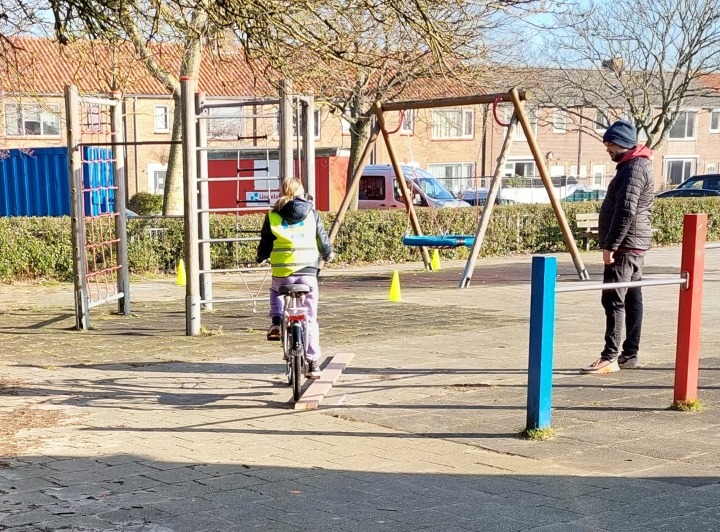 Leerling fietst parkoers op schoolplein 