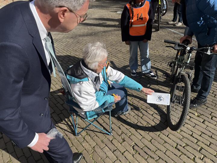 Gedeputeerde kijkt toe bij fietskeuring door vrijwilliger van VVN