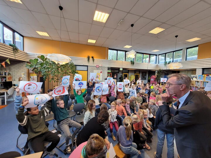 Gedeputeerde bekijkt tekeningen van leerlingen