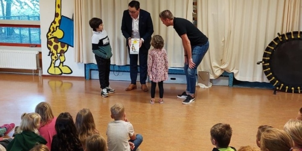 Wethouder De Buck laat muurbord ZVL zien aan leerlingen De Kreeke