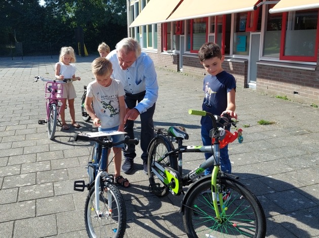 Wethouder Cracau kijkt mee bij het keuren van de fietsen.