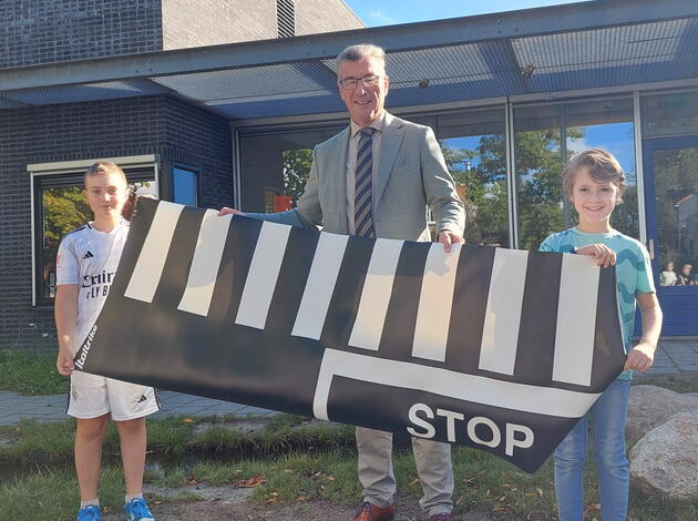 wethouder reikt zebrapadmat uit