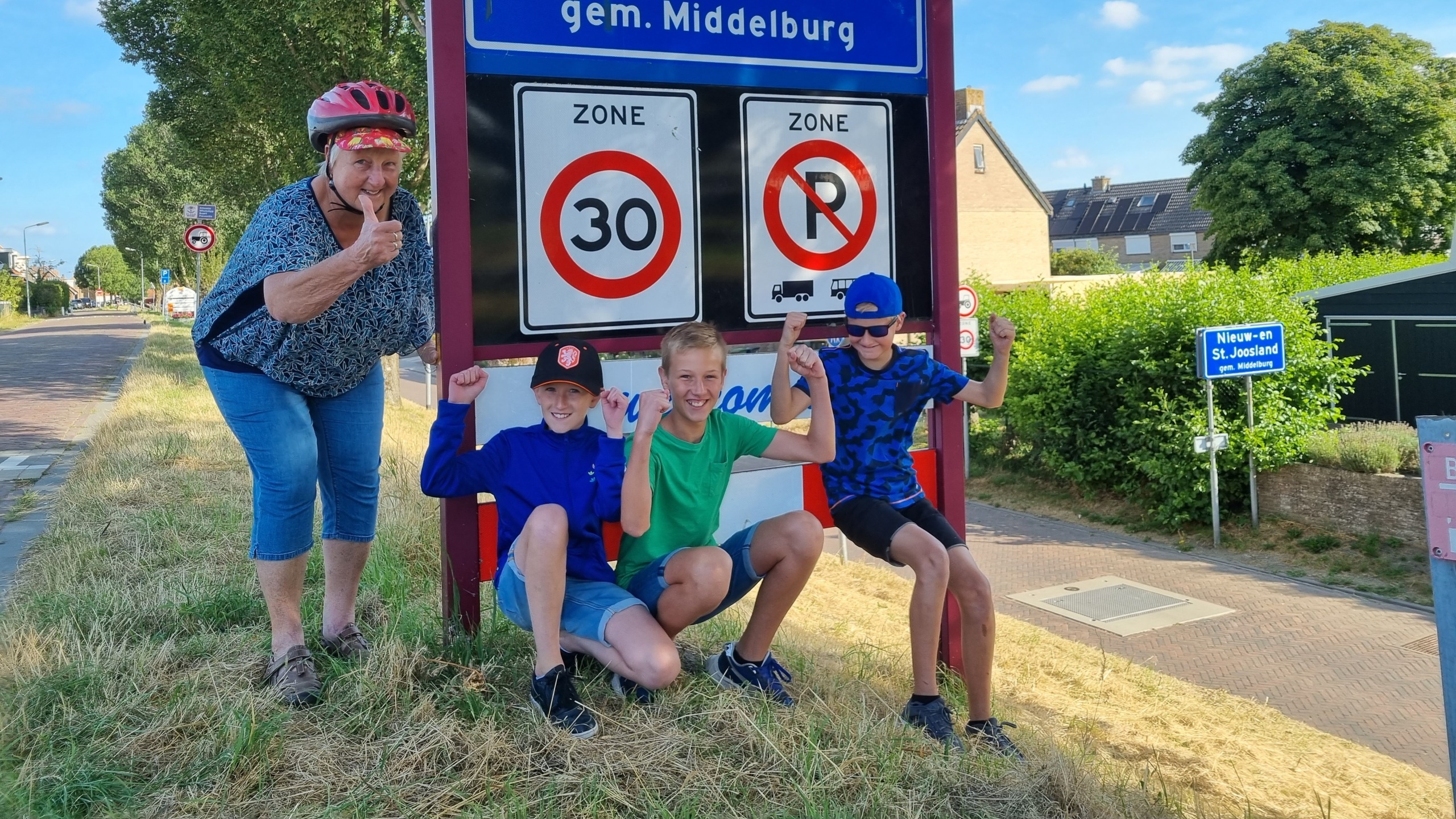 Oma en kleinkinderen poseren voor het plaatsnaambord van Nieuw- en ST. Joosland